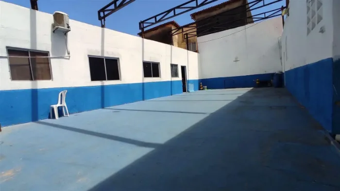 Quadra esportiva da escola com piso pintado em azul e mureta protetora